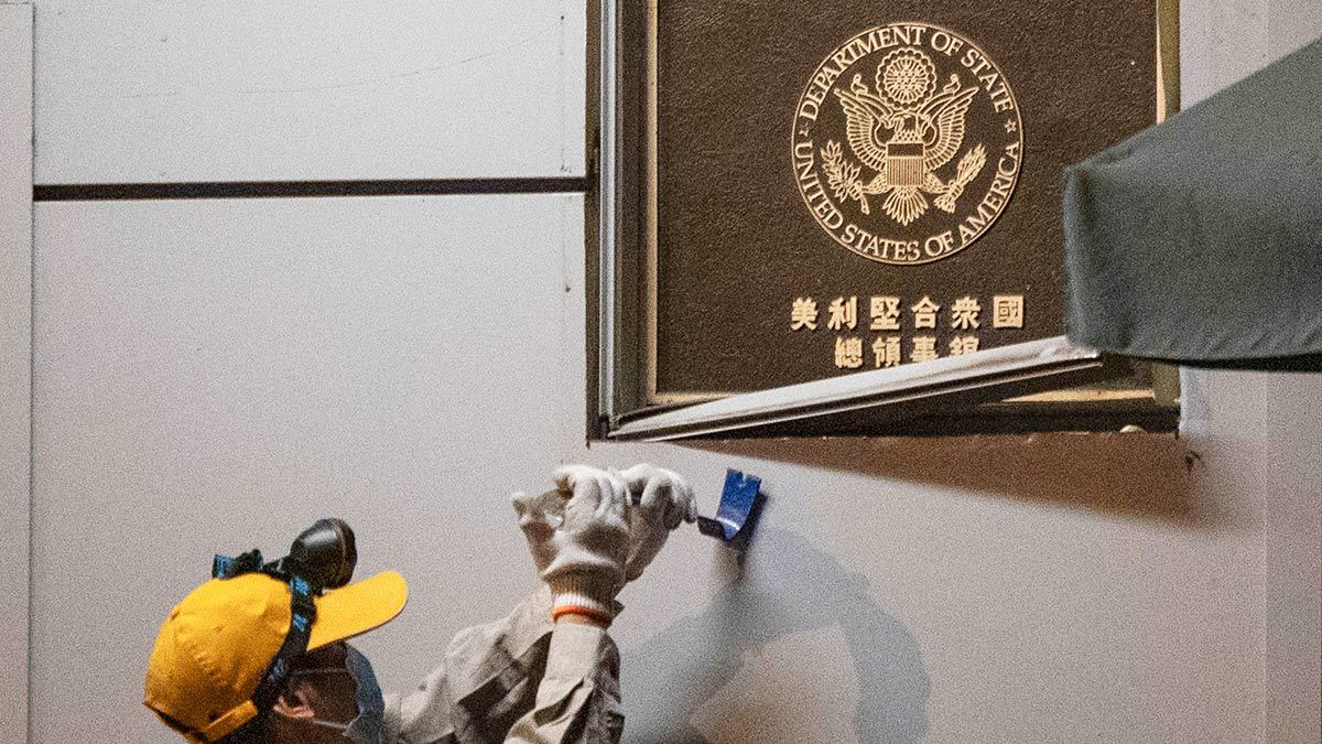Рабочий снимает табличку с надписью «Консульство США» в Чэнду