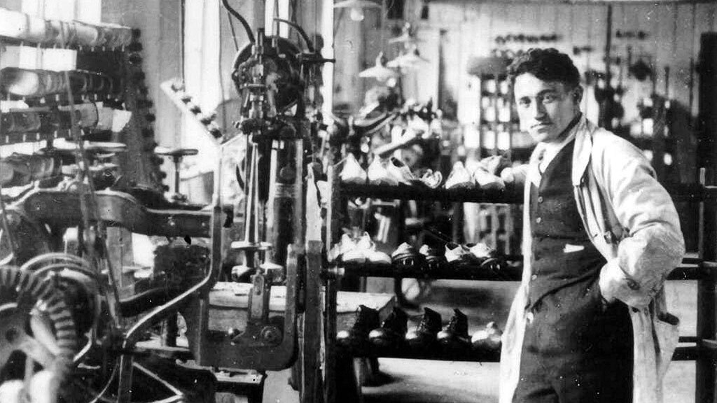 Адольф Дасслер, основатель компании Adidas, держит кроссовки, выставленные в магазине в Германии в 1973 г.