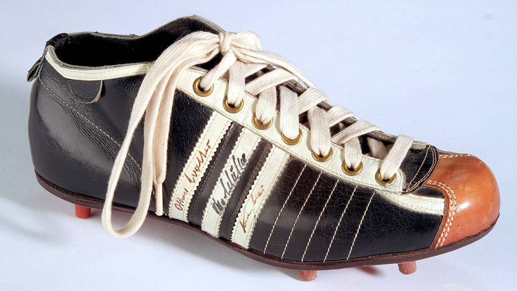 Адольф Дасслер, основатель компании Adidas, держит кроссовки, выставленные в магазине в Германии в 1973 г.