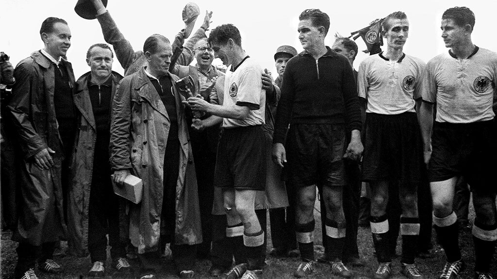 Адольф Дасслер, основатель компании Adidas, держит кроссовки, выставленные в магазине в Германии в 1973 г.