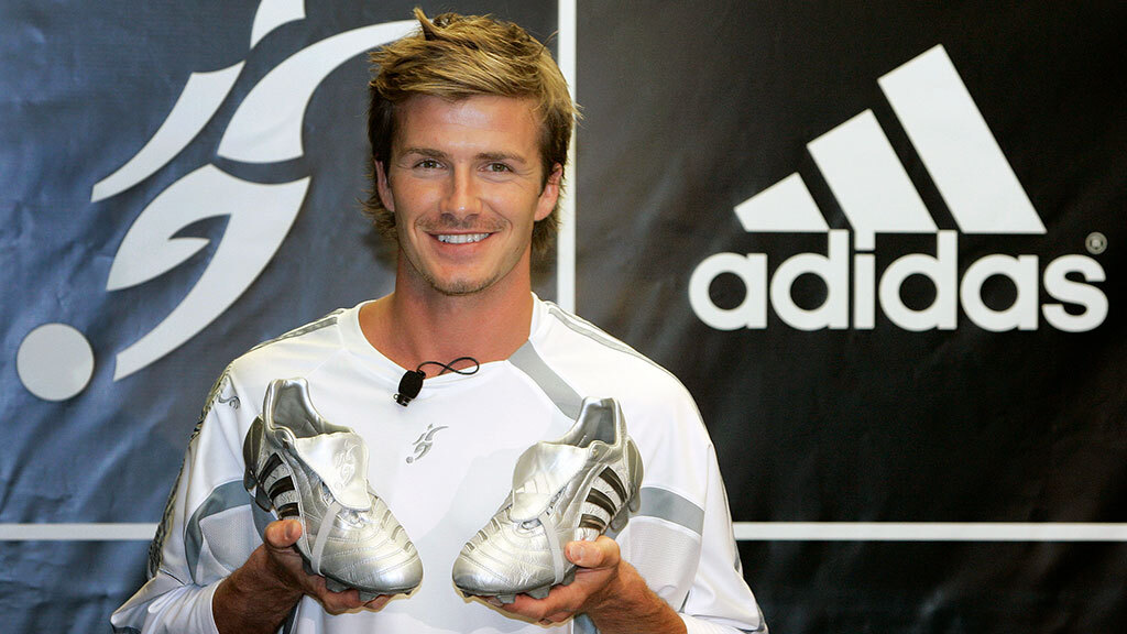 Адольф Дасслер, основатель компании Adidas, держит кроссовки, выставленные в магазине в Германии в 1973 г.