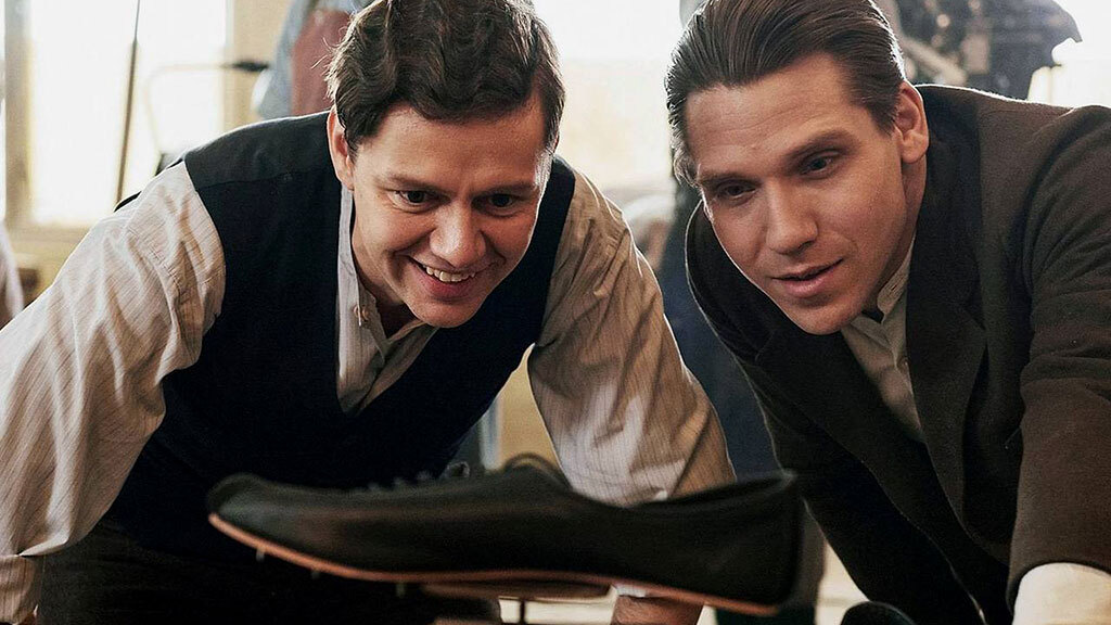 Адольф Дасслер, основатель компании Adidas, держит кроссовки, выставленные в магазине в Германии в 1973 г.