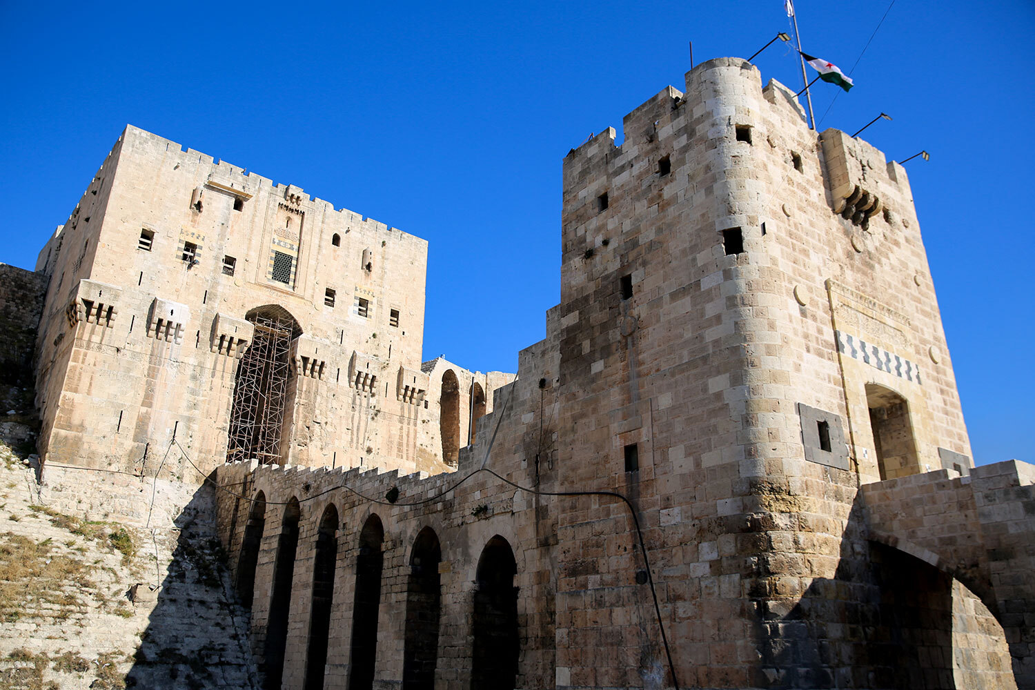 Цитадель в Алеппо (на фото) также получила серьезные повреждения в ходе гражданской войны в Сирии в 2012–2016 гг. Были разрушены средневековые железные двери, всерьез пострадали входная группа, стены и укрепления (писали, что потеряны около 20% сооружения). Цитадель в Алеппо построена в Х в. Наиболее заметную роль она сыграла во времена Крестовых походов, когда попеременно выступала опорным пунктом то рыцарей-крестоносцев, то воинов-мусульман. В 2010-е в цитадели закрепились правительственные войска, противостоявшие террористам: в сирийском Алеппо объект вновь стал символом сопротивления. Он находится под охраной ЮНЕСКО с 1986 г. Всего в Сирии пострадали не менее шести объектов Всемирного наследия.