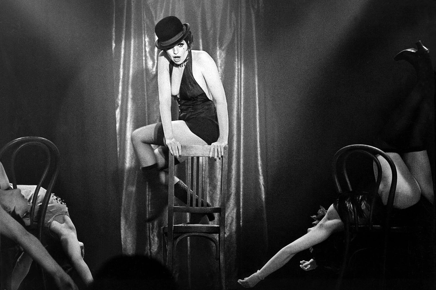 В 1972 г. на экраны вышла музыкальная мелодрама Боба Фосса «Кабаре» (кадр на фото), ставшая главной кинокартиной в жизни Лайзы Миннелли. Работа в ней принесла актрисе премии «Оскар», «Золотой глобус» и BAFTA. Фильм снят о предвоенном Берлине на основе одноименного мюзикла Джона Кандера на стихи Фреда Эбба (1966). В киноверсии Миннелли сыграла певицу и танцовщицу Салли Боулз. Перед этим она 14 раз прослушивалась на роль Салли на Бродвее, но проиграла ее женственной британке Джилл Хэйуорт. В исполнении Лайзы наиболее известными стали песни «Money, Money» («Деньги вертят этим миром») и «Cabaret»: «Жизнь – это кабаре, мой друг».