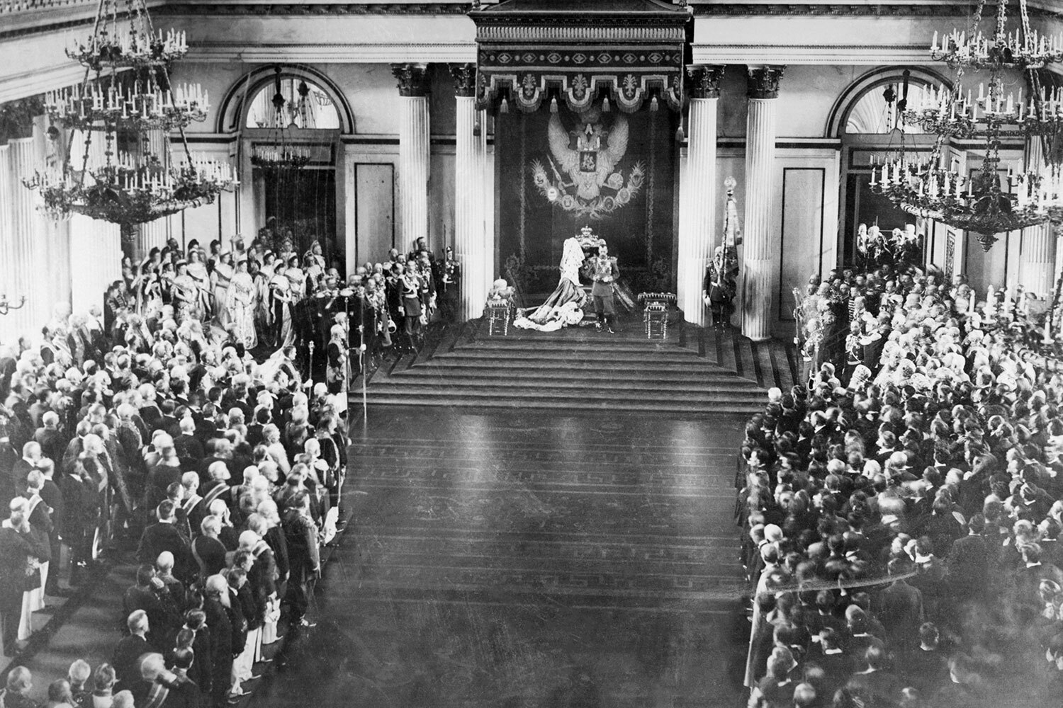 26 марта 1906 г. начались выборы депутатов Государственной думы Российской империи. В результате сложной многоступенчатой процедуры был сформирован первый законодательный орган страны. И хотя ему не удалось проработать и трех месяцев, создание Госдумы стало важной вехой политической трансформации общества. Как избирали первых российских парламентариев – в галерее «Ведомостей».Появление Государственной думы стало результатом Первой русской революции 1905 г. Массовые выступления рабочих, крестьян и интеллигенции, а также всеобщая забастовка вынудили власть пойти на уступки. Николай II хотел смягчить обстановку и отвлечь народ от революционных настроений, сохранив самодержавие.На фото: Николай II во время тронной речи на церемонии открытия Государственного совета и Государственной думы в Зимнем дворце, 27 апреля 1906 г.