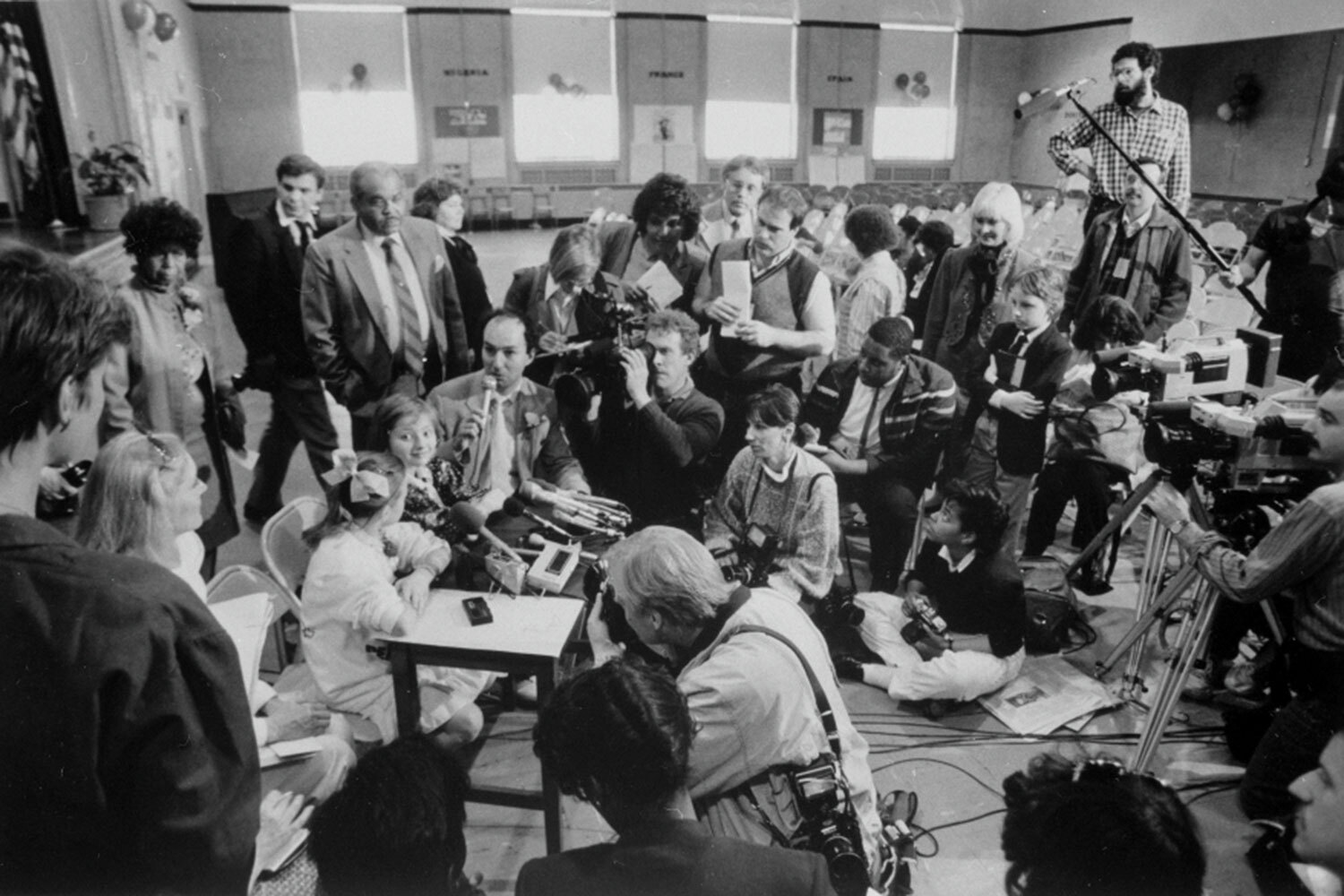 Катя идеально соответствовала критериям: она училась в английской спецшколе, свободно говорила по-английски, имела актерский опыт (девочка снялась в фильмах «Живая радуга», «Сильная личность из 2А», «Детство Бемби»), была общительной и обаятельной. Перед поездкой ей несколько месяцев рассказывали о США и местных обычаях, учили, как отвечать на вопросы журналистов и обходить «скользкие» темы – например, о дефиците продуктов в советских магазинах.На фото: американские журналисты берут у Кати Лычевой (в центре) интервью.