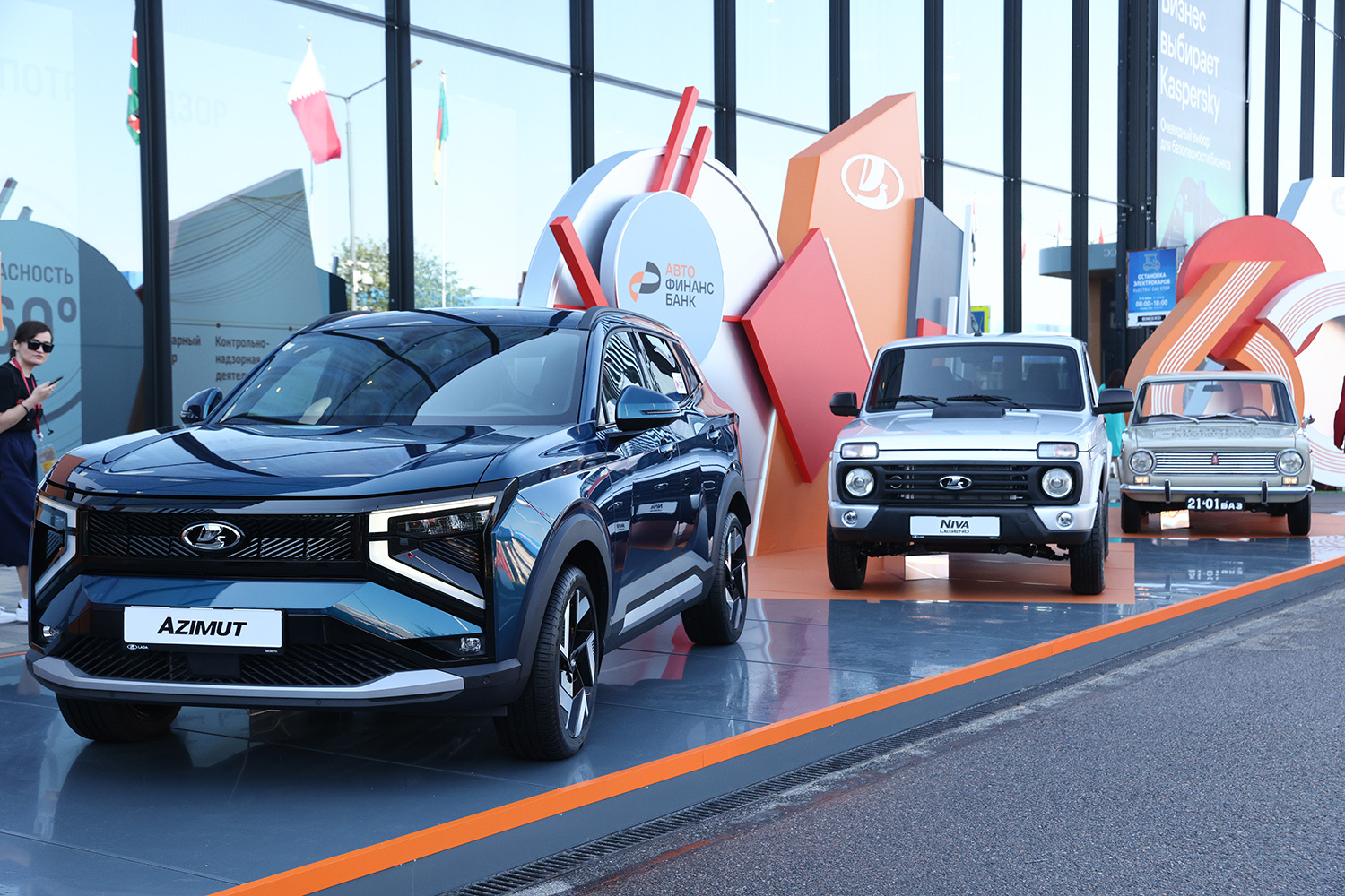 На ПМЭФе «АвтоВАЗ» развернул масштабную экспозицию, главным героем которой стал  кроссовер Lada Azimut. Серийное производство автомобиля запланировано на сентябрь 2026 г.  В новой модели установят эксклюзивную технологию обогрева межбоковых зеркал, заявил вице-президент компании Сергей Громак. На стенде также показаны обновленная Niva Legend и классический ВАЗ-2101.