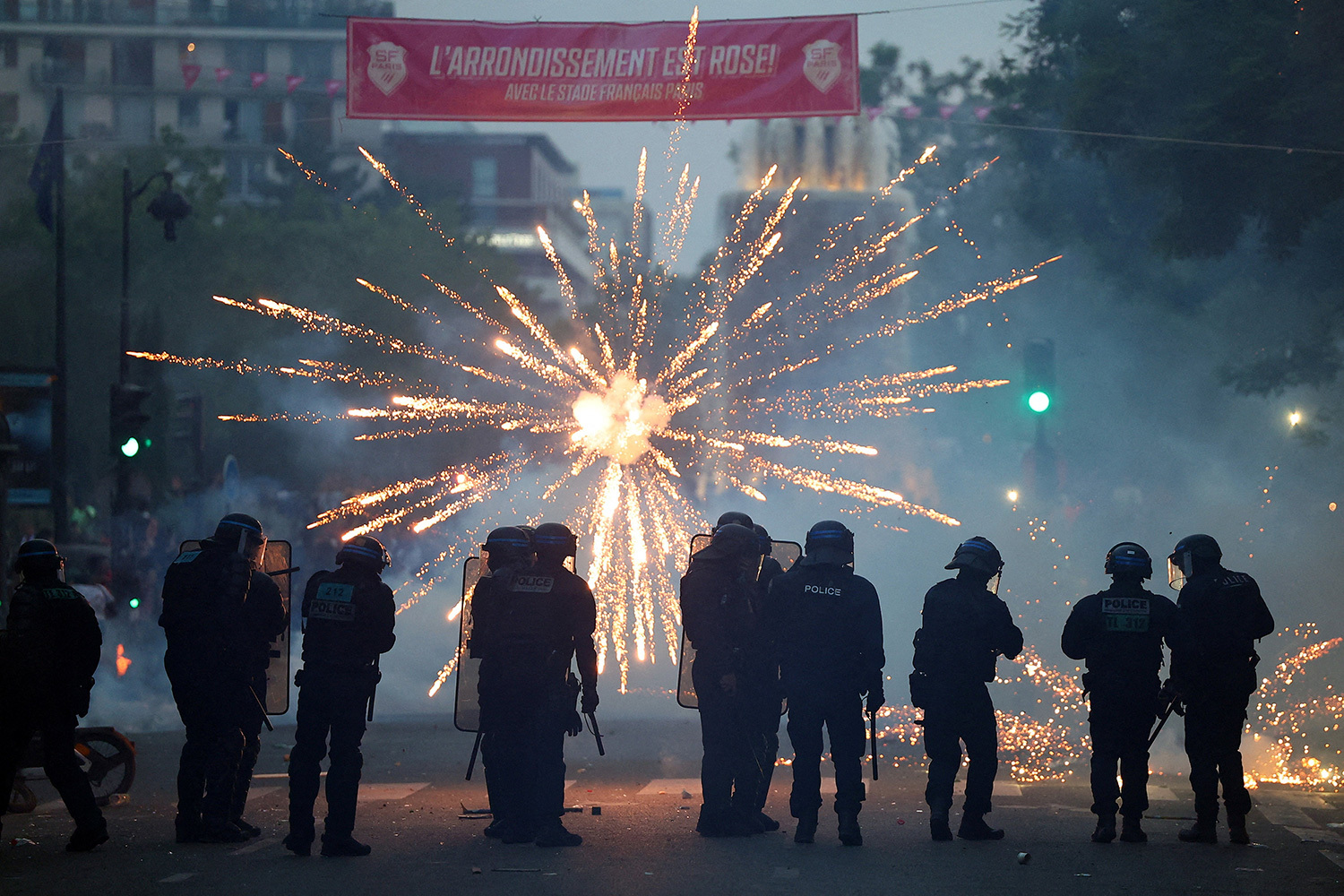 30 июня 2026 г. Полицейские возле стадиона «Парк де Пренс» во время финала Лиги чемпионов УЕФА, где ПСЖ обыграл английский «Арсенал», а болельщики в честь победы запускают фейерверк, Париж.