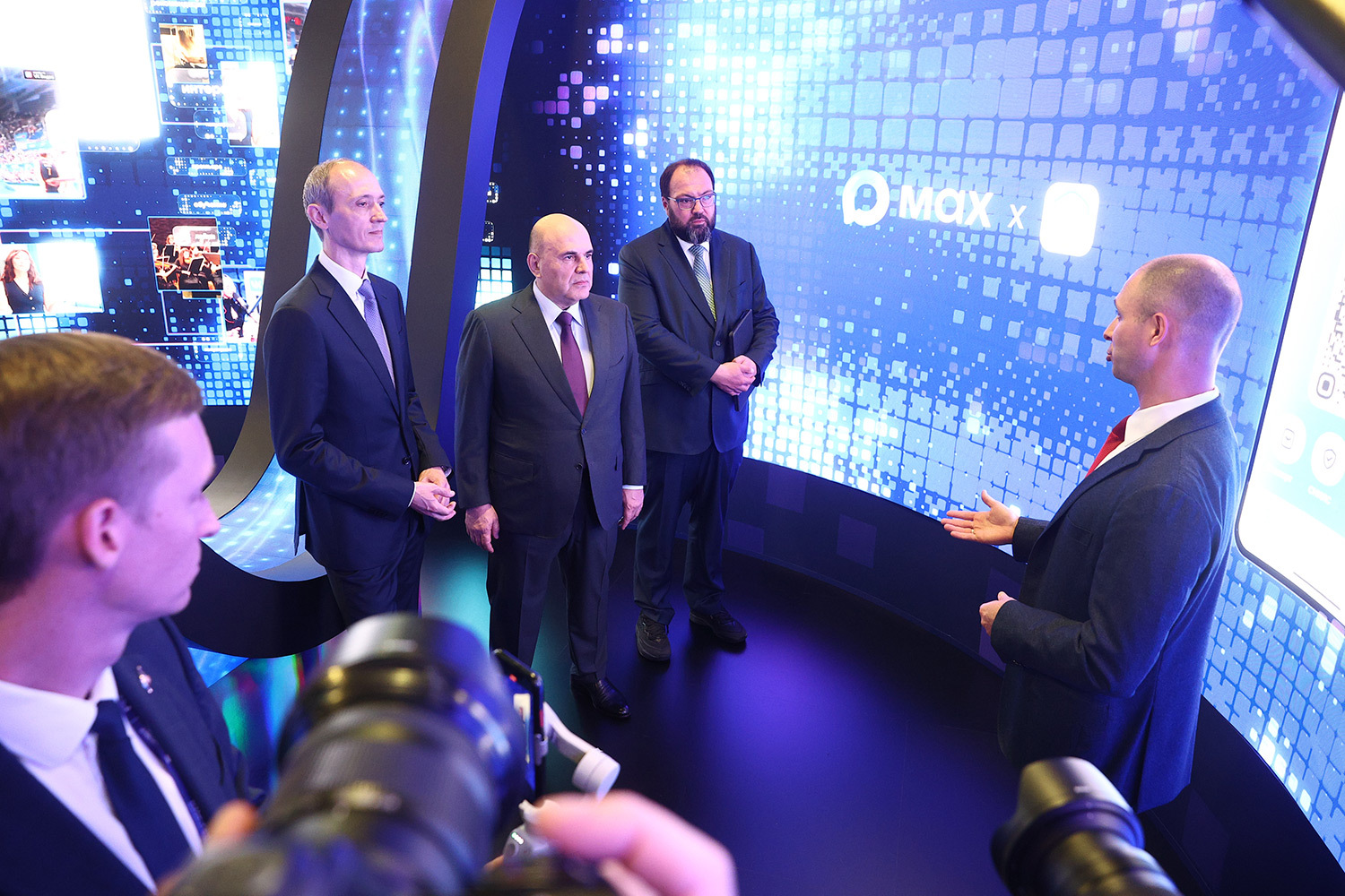6 октября в национальном центре «Россия» открылся IТ-форум «Цифровые решения – 2026». Главным событием первого дня стала пленарная сессия «Результаты. Возможности. Перспективы» с участием председателя правительства РФ Михаила Мишустина. В присутствии премьер-министра президент «Ростелекома» Михаил Осеевский дал старт работе трансевразийской линии связи TEA Next – крупнейшему инфраструктурному проекту в истории российского телекома. Эта волоконно-оптическая магистраль протяженностью 7600 км, созданная на базе отечественных технологий, свяжет западные и восточные границы страны для транзита трафика между Европой и Азией. Кроме того, во время осмотра стендов компаний Мишустин признался, что пользуется сервисами VK.На фото: вице-премьер РФ Дмитрий Григоренко, председатель правительства Михаил Мишустин, глава Минцифры Максут Шадаев и гендиректор VK Владимир Кириенко.